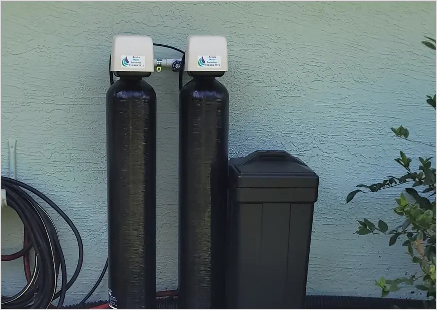 Two water softeners are next to a black tank.