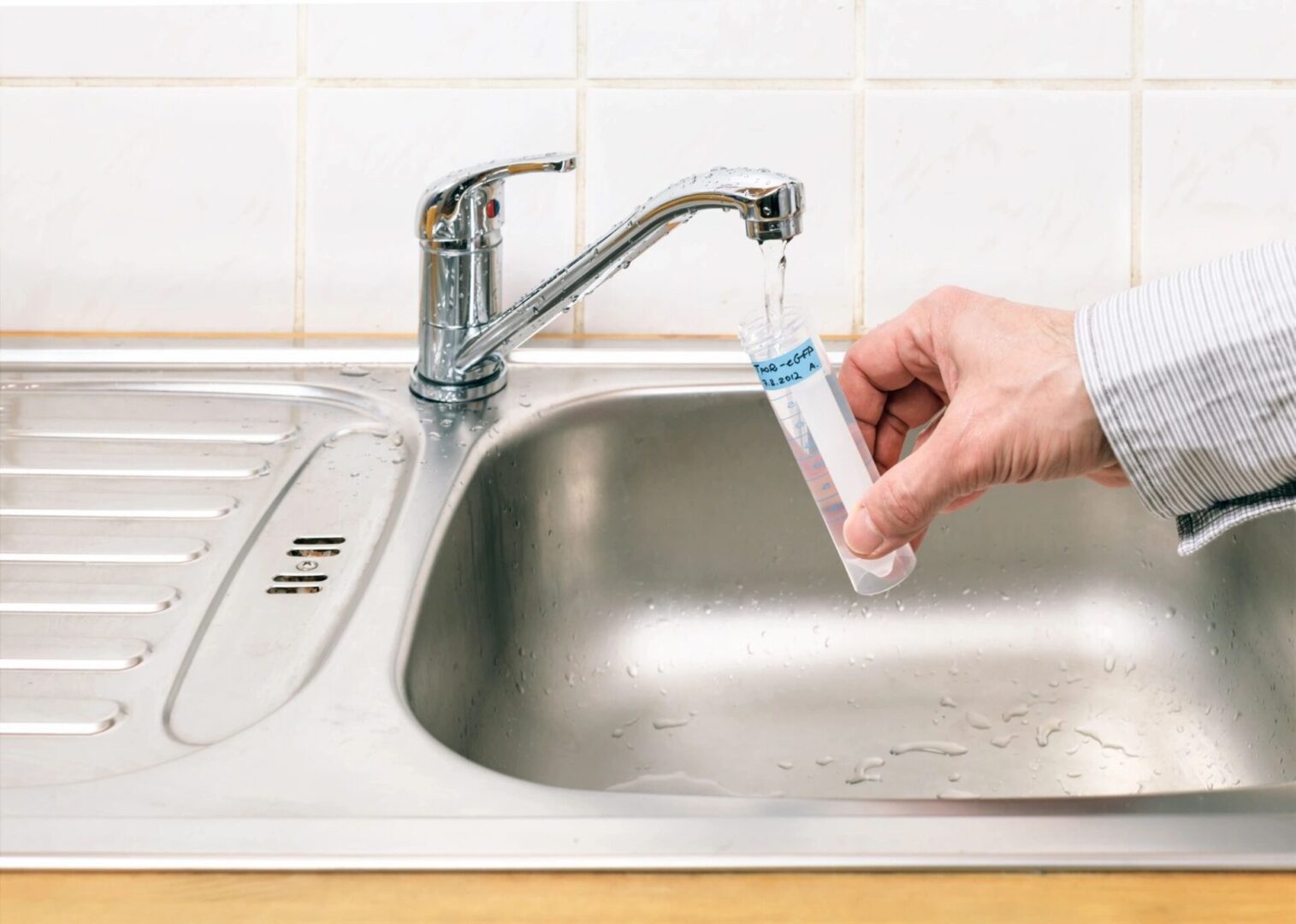 A person is filling up a glass with water from the sink.